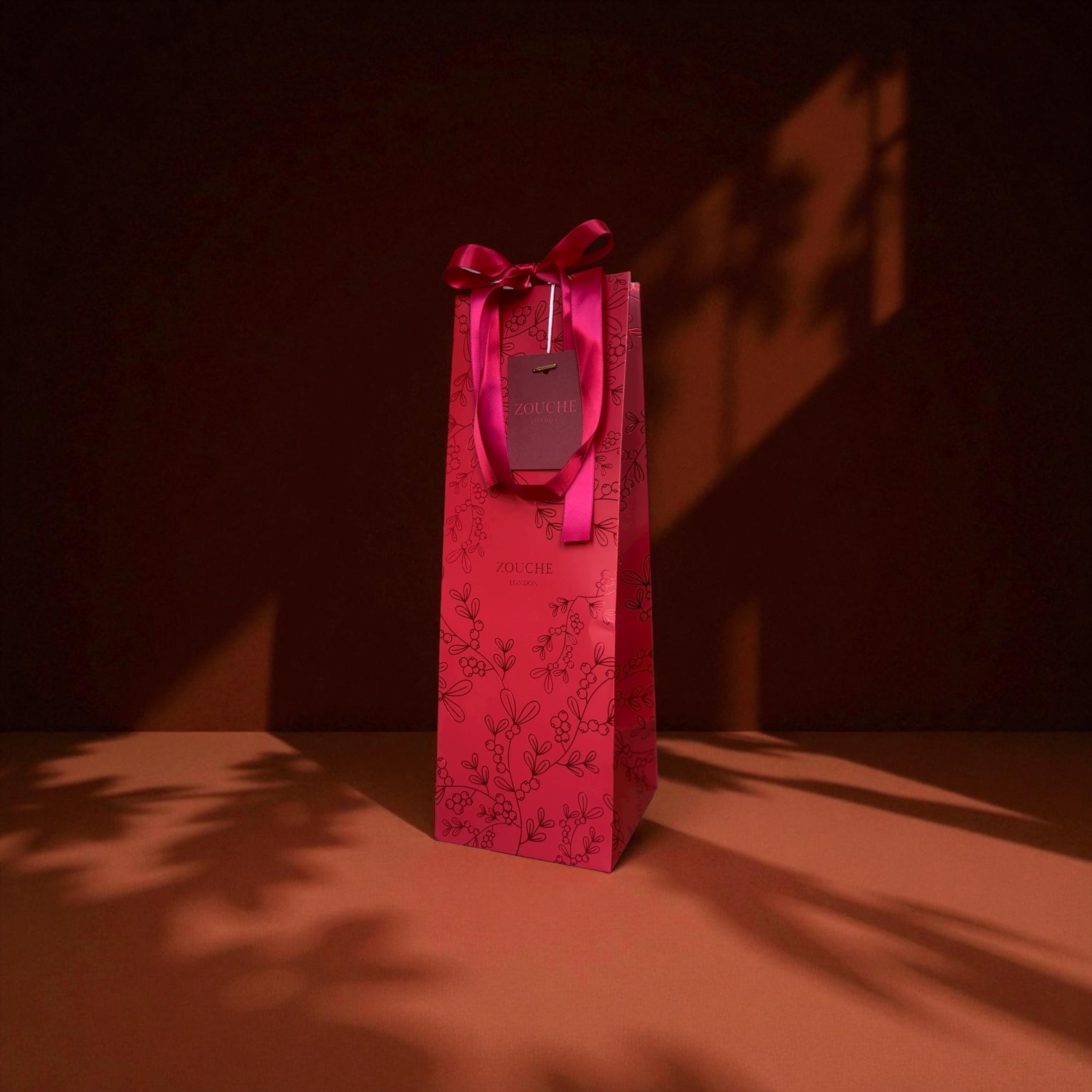 Red bottle bag with satin ribbon handles and bow. 